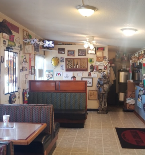 Cozy diner interior with booths, vintage decor, and a figure in a suit near the counter. A TV is mounted on the wall.
