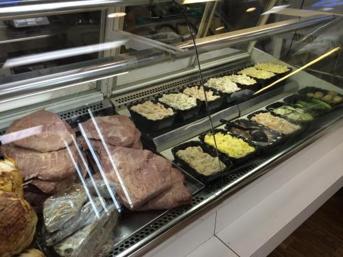 A deli display case featuring various meats and salads in black containers, with sliced meats in the foreground.