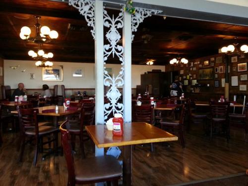 A cozy restaurant interior with wooden tables, chairs, and vintage decor, featuring a few patrons and warm lighting.