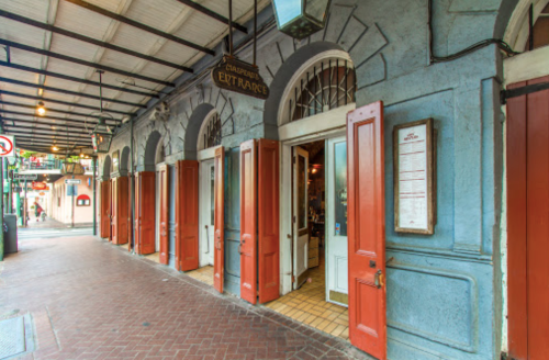 Colorful building with red doors and a sign reading "Entrance," set in a charming street with warm lighting.