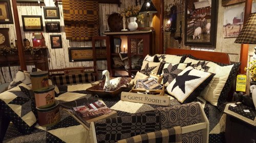 Cozy guest room with a quilted bed, decorative pillows, and rustic decor, featuring a warm, inviting atmosphere.