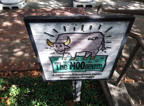 Sign for "The MOOseum," a children's educational center in Montgomery, Alabama, featuring a cartoon cow illustration.