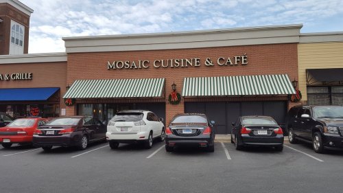 Exterior of Mosaic Cuisine & Café with striped awnings and parked cars in front.