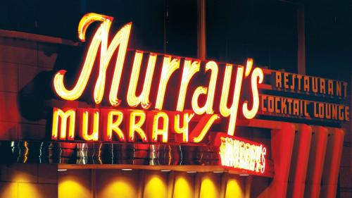 Neon sign for Murray's Restaurant and Cocktail Lounge, glowing brightly against a dark background.