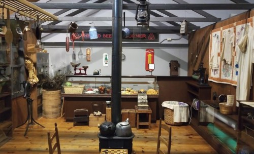 A vintage kitchen interior featuring a stove, wooden furniture, and various antique kitchenware and decor.