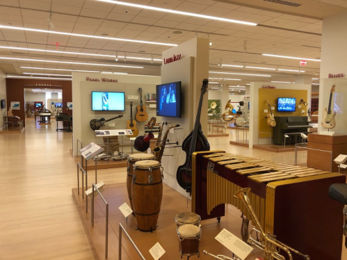 Interior of a museum showcasing various musical instruments and displays, including screens and exhibits.