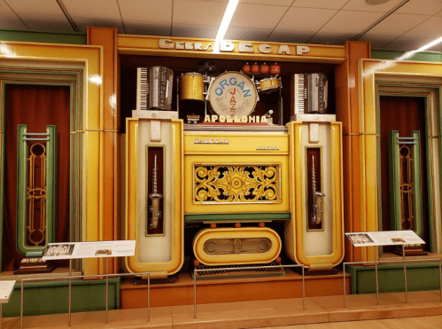 Colorful vintage organ display featuring various instruments and decorative elements in a museum setting.