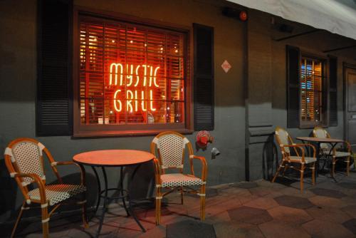 A cozy outdoor dining area with empty chairs and a glowing "Mystic Grill" sign in the window at night.