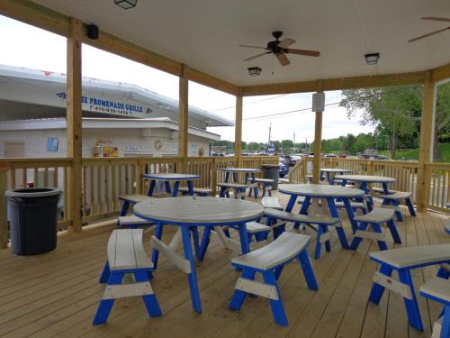 Outdoor dining area with wooden tables and benches, featuring a covered porch and a view of a restaurant in the background.