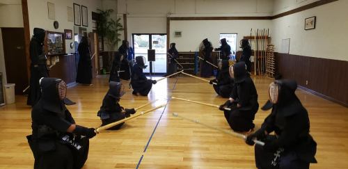 A kendo practice session with multiple practitioners in traditional attire, engaged in sparring in a dojo.