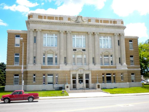Historic courthouse building with a grand facade, featuring large windows and decorative stonework, set against a blue sky.