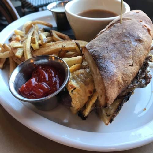 A plate with a sandwich, fries, and a small bowl of dipping sauce.