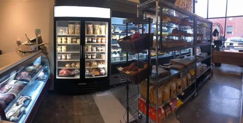 A grocery store interior featuring refrigerated displays, shelves of baked goods, and various packaged items.