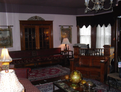 A vintage living room with ornate furniture, a chandelier, and decorative rugs, featuring a warm, inviting atmosphere.