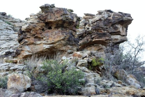 Rock formations with rugged textures and sparse vegetation in a natural landscape.