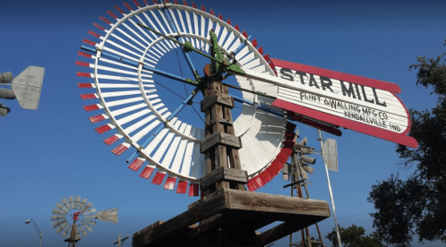 A colorful windmill with "Star Mill" sign, surrounded by other windmills against a clear blue sky.