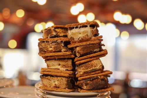 A stack of toasted s'mores with melted marshmallow and chocolate, set against a blurred background of warm lights.