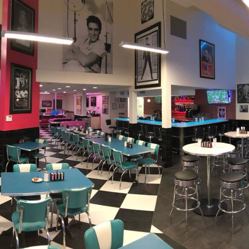 Retro diner interior with turquoise chairs, black and white checkered floor, and vintage Elvis memorabilia on the walls.