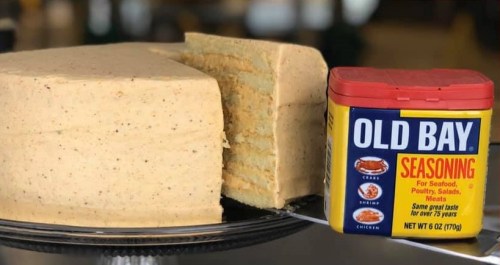 A layered cake next to a container of Old Bay seasoning, showcasing a unique flavor combination.