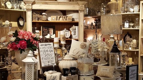 A cozy display of home decor items, including signs, vases, and decorative pillows, arranged on shelves.