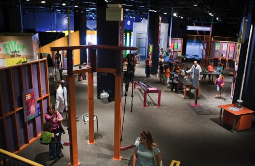 A vibrant science museum exhibit with families exploring interactive displays and activities in a spacious area.