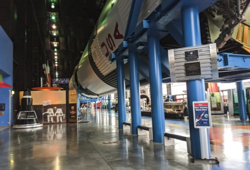 Interior of a space museum featuring a large rocket, display panels, and astronaut exhibits.