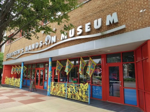 Exterior of the Children's Hands-On Museum, featuring colorful flags and a welcoming entrance.