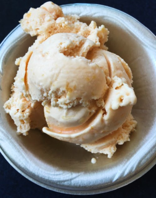 A scoop of creamy orange ice cream in a small bowl.