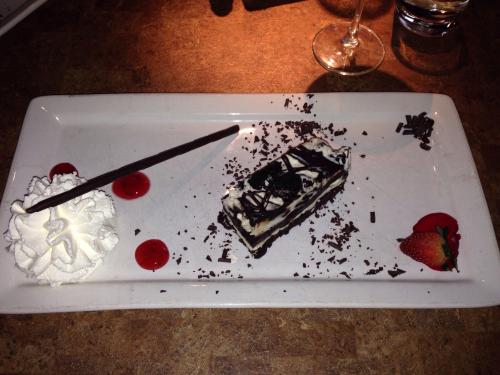 A dessert plate featuring a chocolate cake slice, whipped cream, chocolate shavings, and strawberries with sauce.