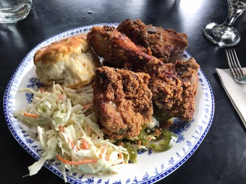 A plate of fried chicken, coleslaw, and a biscuit on a decorative blue and white plate.