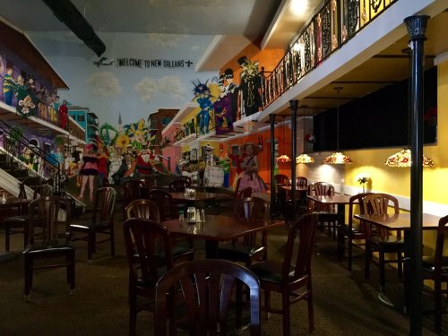 A vibrant restaurant interior featuring colorful murals, wooden tables, and decorative lighting.
