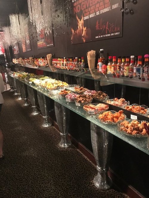 A long buffet table filled with various dishes and sauces, elegantly displayed under sparkling decor.