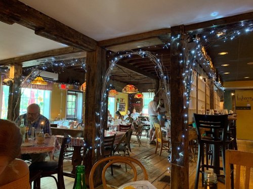 Cozy restaurant interior with wooden beams, twinkling lights, and tables set for dining. Warm, inviting atmosphere.
