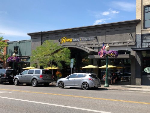 Exterior of Honey Eatery & Social Club, featuring outdoor seating, colorful flowers, and a clear blue sky.