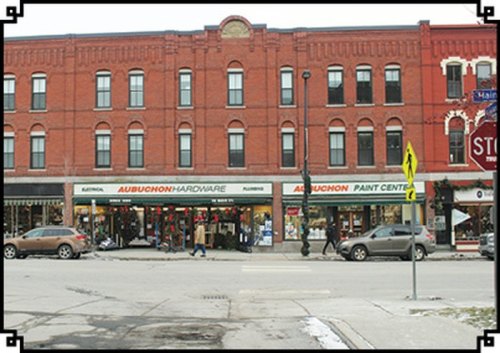 A brick building with two storefronts: Aubuchon Hardware and Aubuchon Paint Centre, along a snowy street.