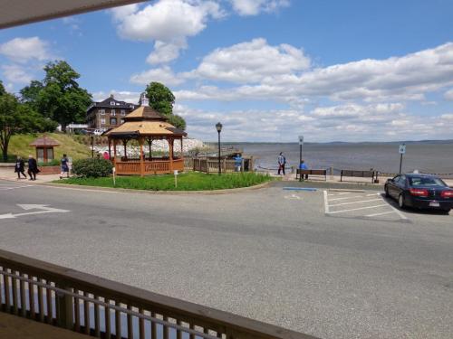 A scenic view of a waterfront area featuring a gazebo, walking path, and people enjoying the outdoors under a blue sky.