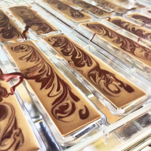 Close-up of chocolate bars with intricate swirls of dark chocolate on a glossy surface.