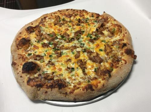 A freshly baked pizza topped with cheese, grilled chicken, and green onions on a golden crust.
