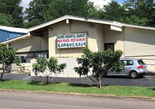 Exterior of a building featuring a sign for "Super Oriental Market" and "Red Pearl Restaurant," surrounded by trees.