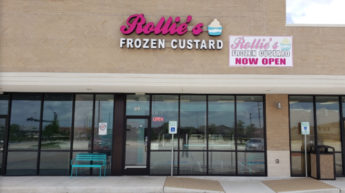 Exterior of Rollie's Frozen Custard shop, featuring a bright sign that says "Now Open" and a welcoming entrance.