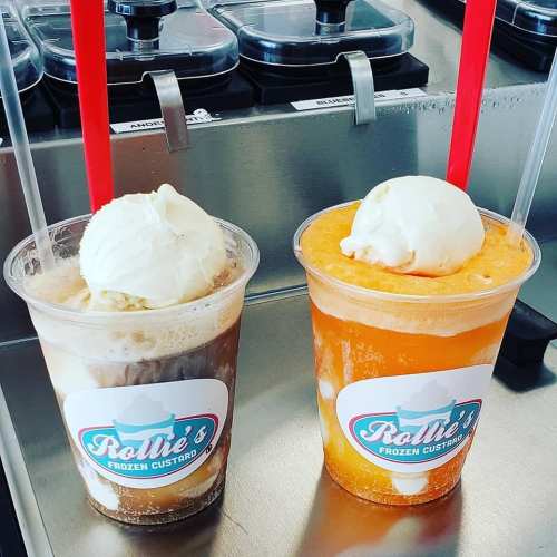 Two cups of frozen custard drinks, one chocolate and one orange, each topped with a scoop of vanilla ice cream and red straws.