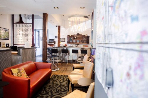 A cozy, modern lounge area with a red sofa, wooden beams, and a kitchen bar in the background.