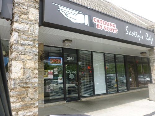 Exterior of Scotty's Cafe with a stone facade, large windows, and an "OPEN" sign.