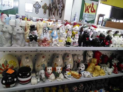 A display of various ceramic figurines, including animals and decorative items, arranged on shelves.
