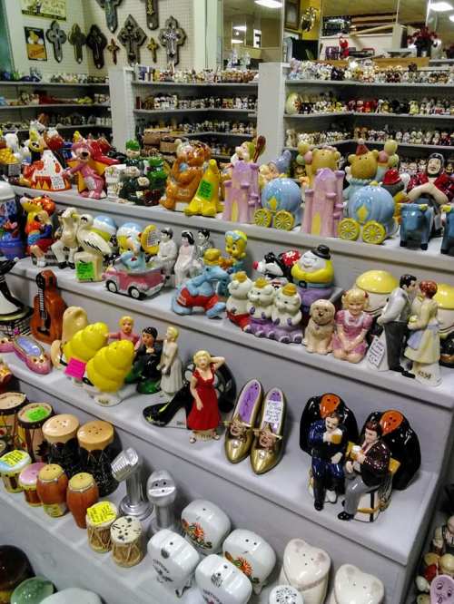 A colorful display of various decorative figurines and salt shakers arranged on shelves in a store.