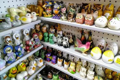 A colorful display of various ceramic figurines, including owls, birds, and other animals, arranged on shelves.
