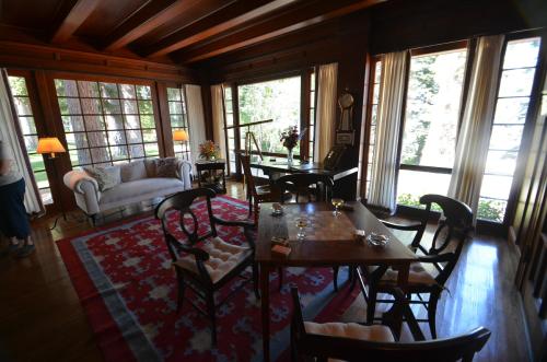 Cozy living room with wooden beams, a sofa, a table, and large windows overlooking a natural landscape.