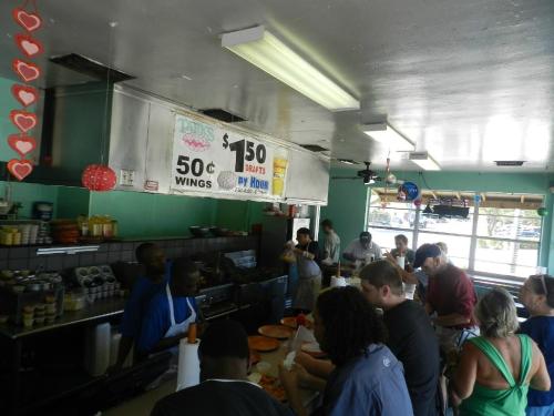 A busy diner with customers at the counter, enjoying food and drinks, and colorful decorations hanging from the ceiling.
