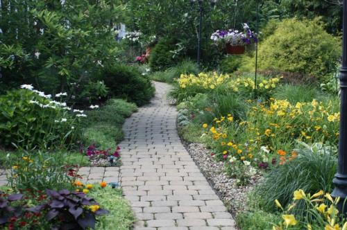A winding stone path through a vibrant garden filled with colorful flowers and lush greenery.