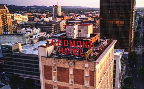 Aerial view of the Redmont Hotel rooftop with city skyline in the background during sunset.